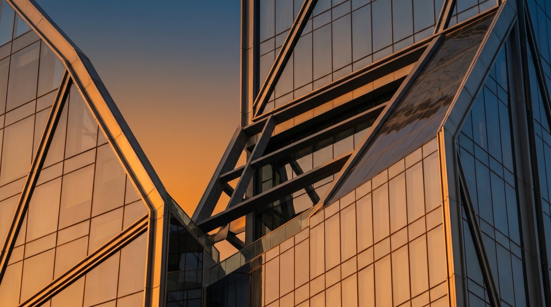 Modernes Hochhaus in Dubai im Abendlicht, Glasfassade mit goldenen Reflexionen vor tiefblauem Himmel