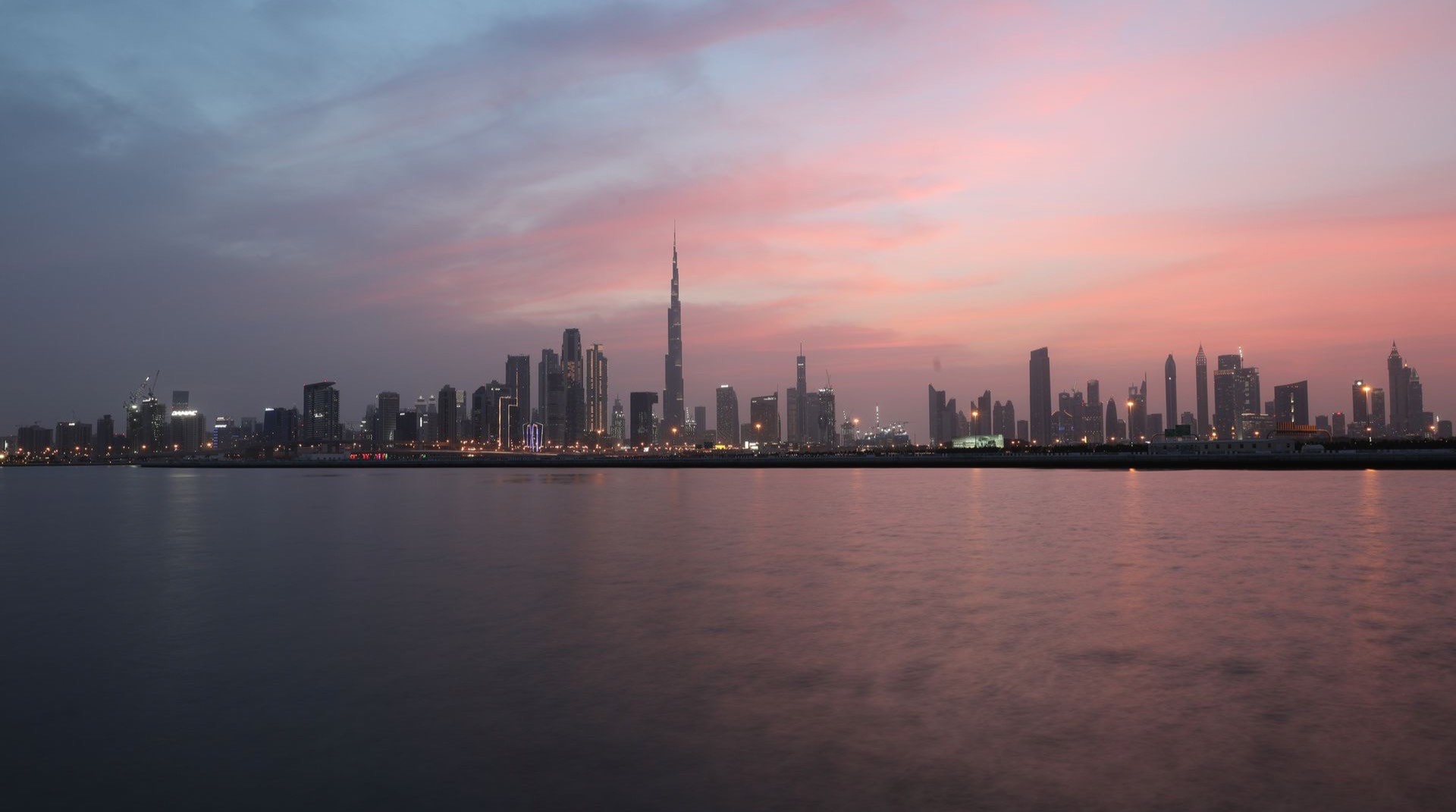 Wohntürme von Dubai Sports City rund um die grünen Sport- und Golfanlagen in der Abenddämmerung