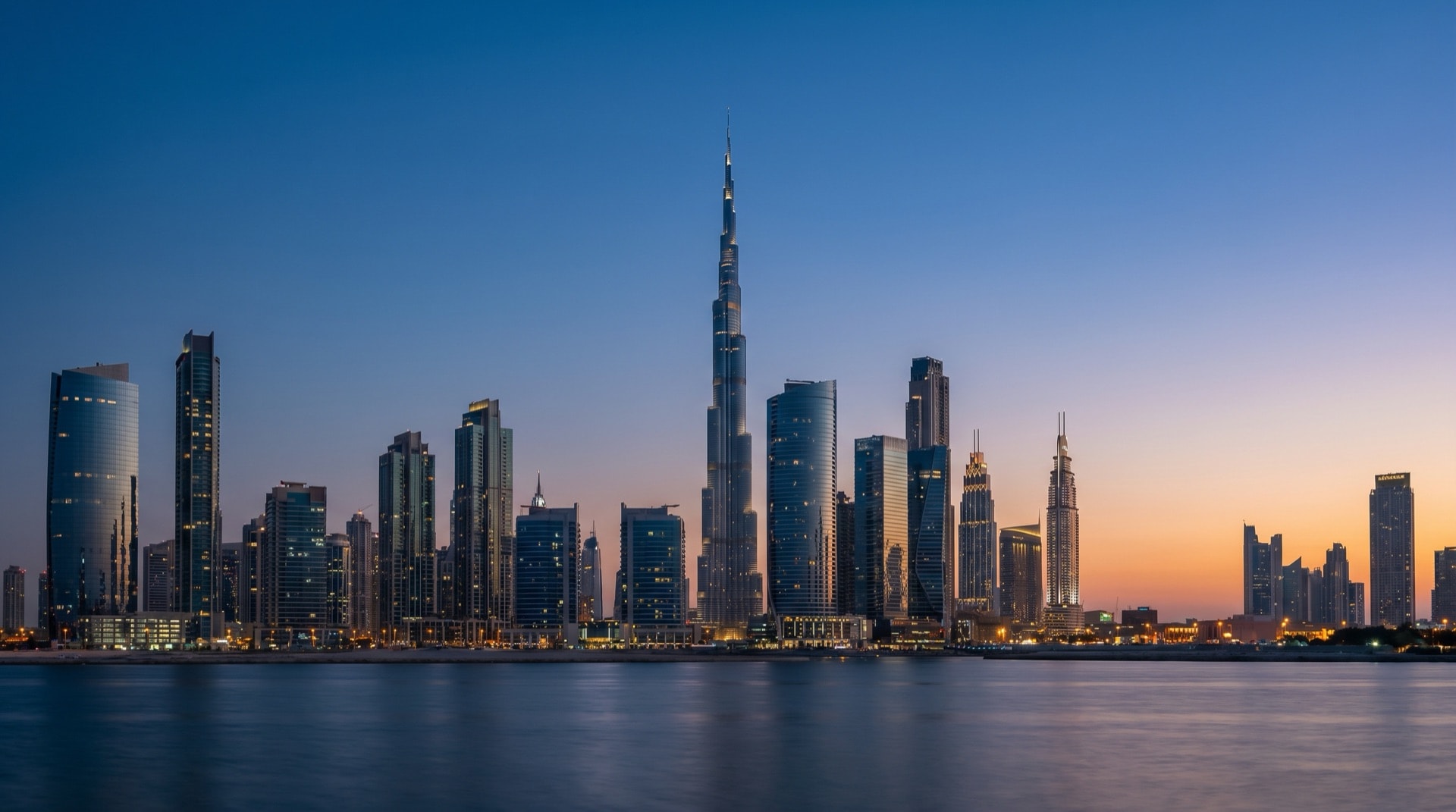 Moderne Wohnarchitektur in Dubai im goldenen Abendlicht, Glas und Naturstein, ruhiges Wasser im Vordergrund