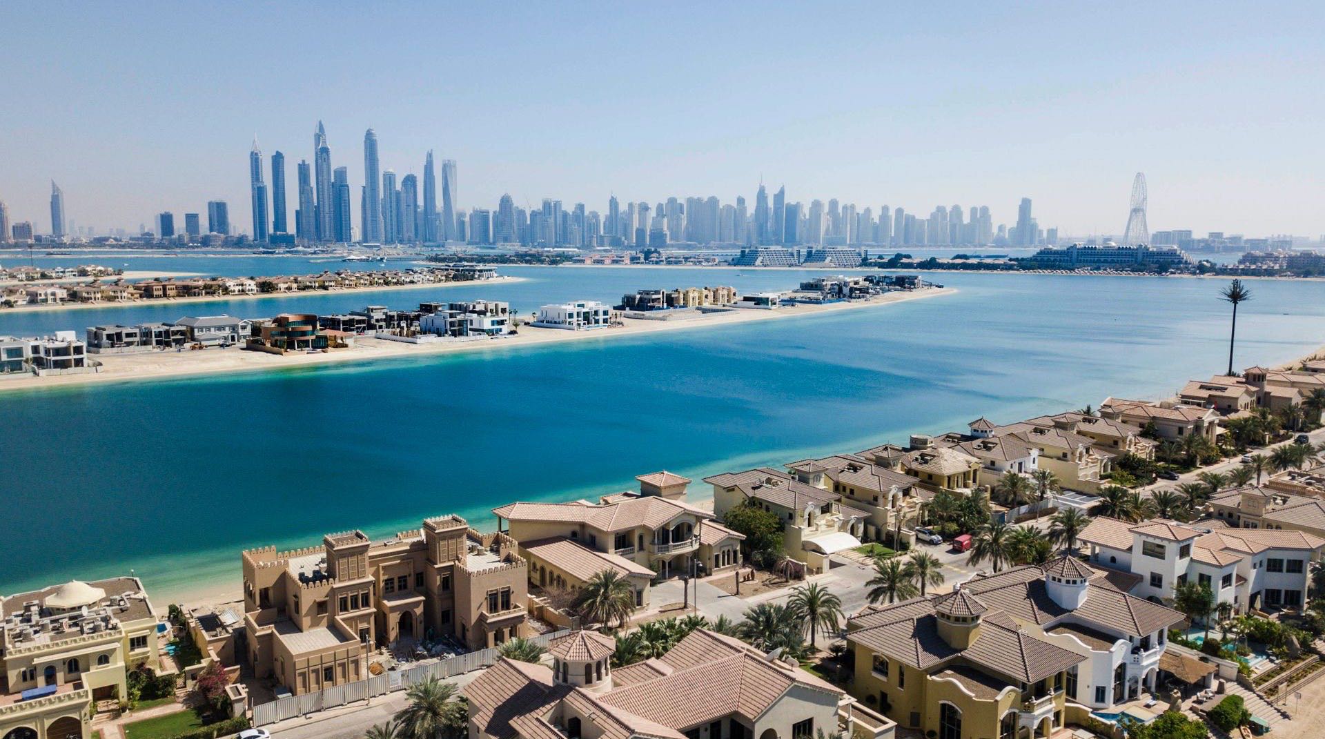 Weitläufige Wohnentwicklung in Dubailand bei Abenddämmerung, niedrige bis mittelhohe Apartmentblöcke und Baukräne vor dem offenen Landesinneren